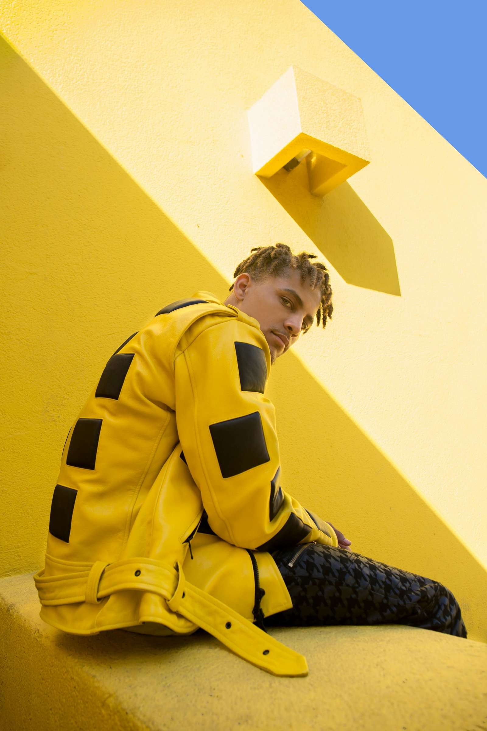 Man wearing a yellow statement jacket against architectural walls