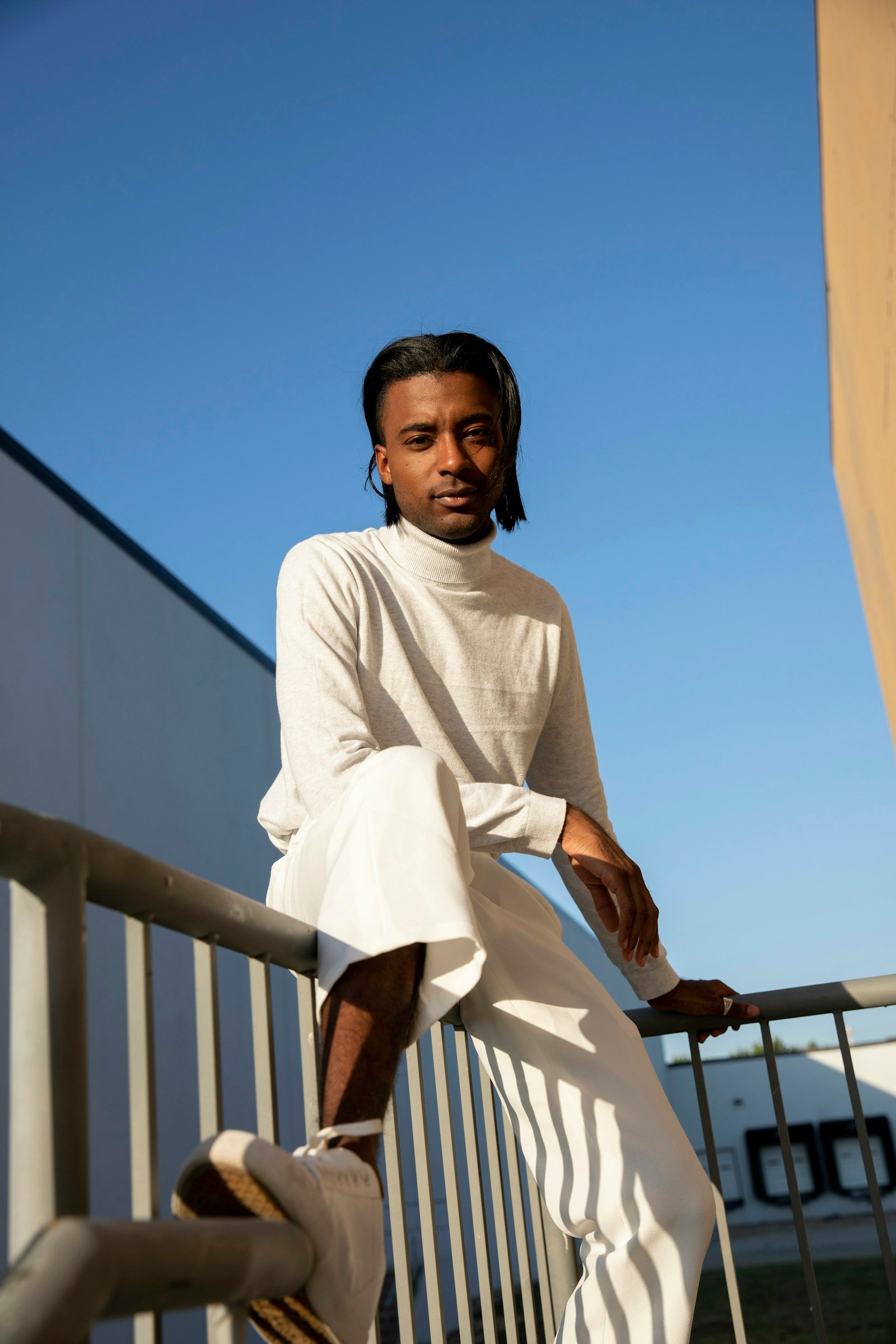 Man in an all-white minimal outfit on a terrace