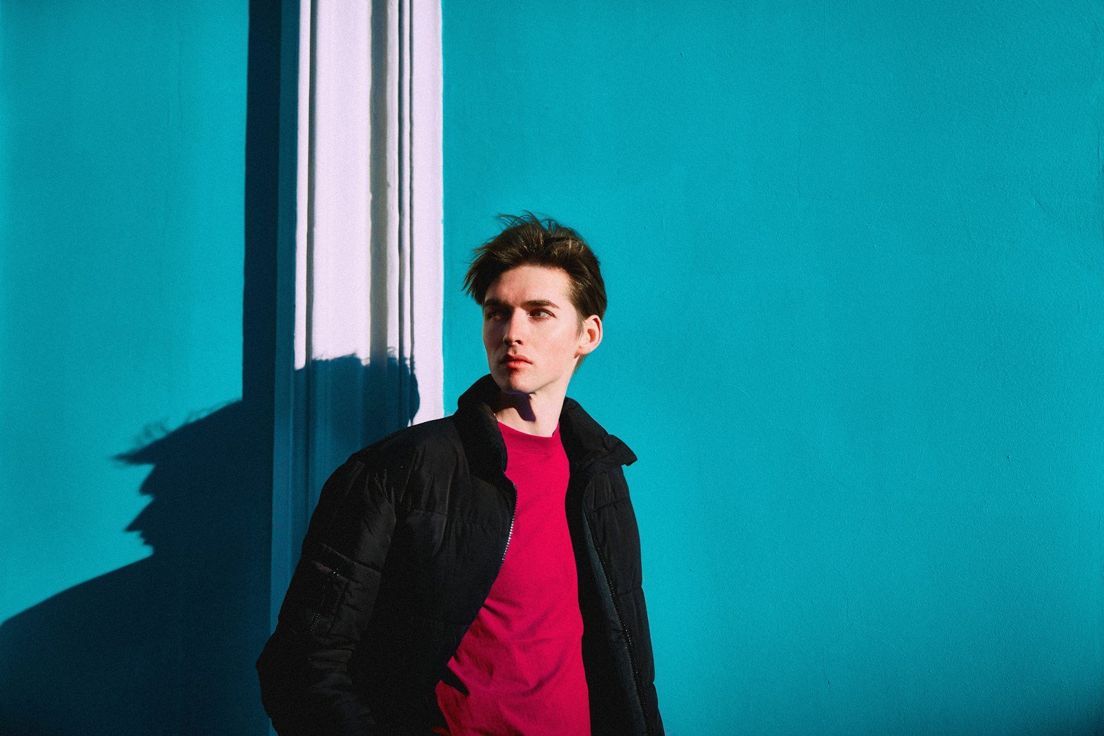 Man in a dark jacket against a blue wall